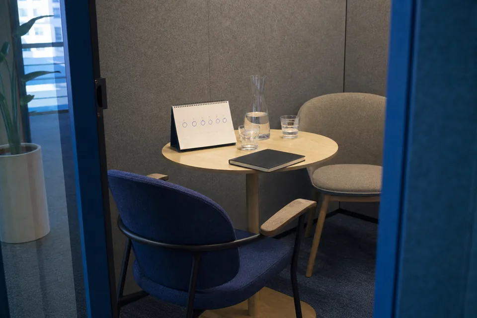 Small interview booth with two chairs, a desk calendar with circled days and a carafe of water